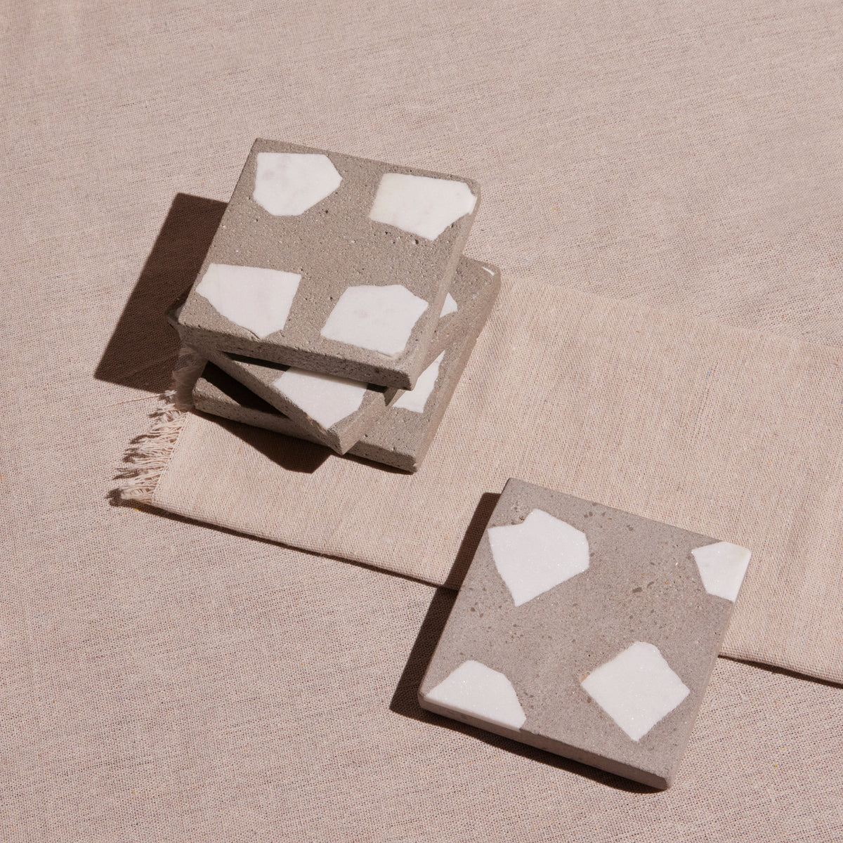 Concrete coasters with white pattern on a beige surface