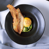 Dish with fried items on a black plate, placed on a white surface.