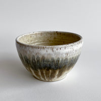 Ceramic bowl with light and dark neutral glaze details on a white background