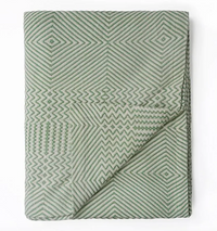 Folded green quilt with geometric pattern on a white background