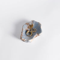 Gold jewelry in a decorative stone dish with a light gray background
