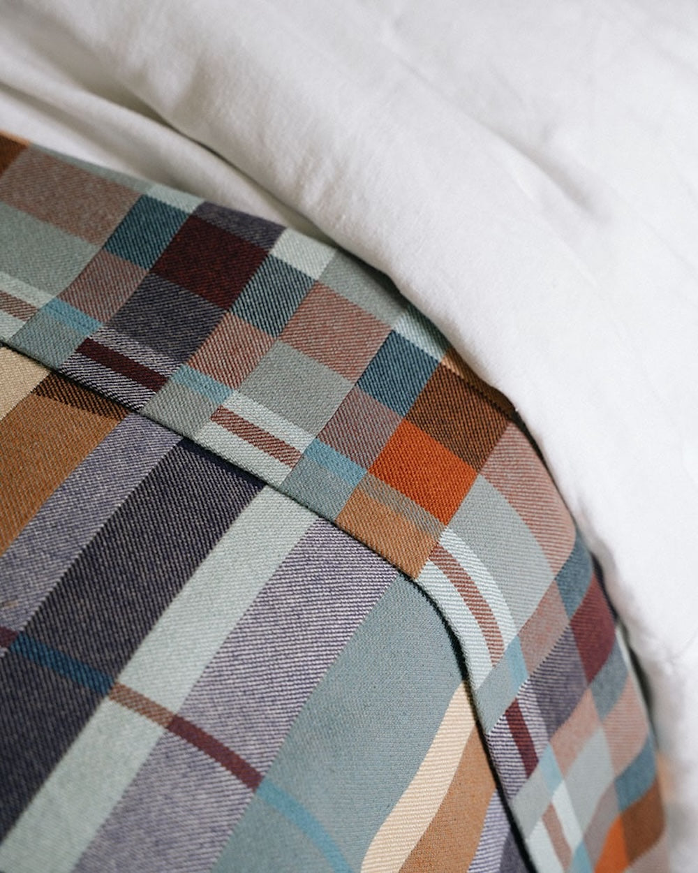 Plaid patterned blanket on a bed with white sheets