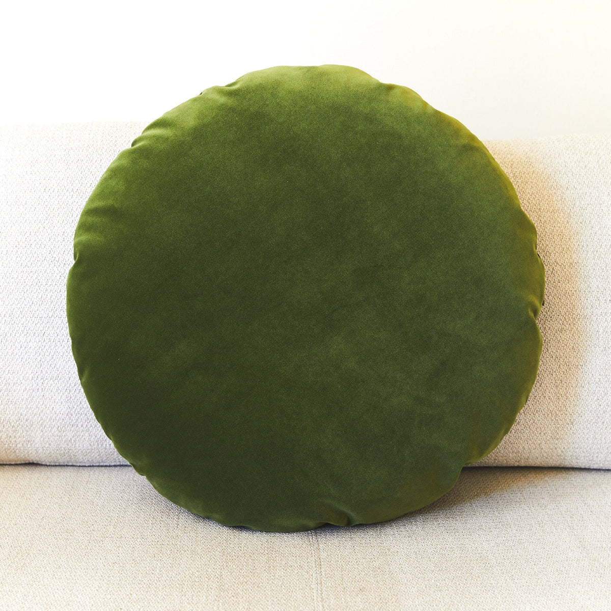 Green round pillow on a beige sofa