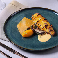 Gourmet dish on a blue plate with a white napkin and cutlery.