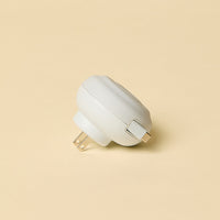 White wall plug and charging cord on a beige background