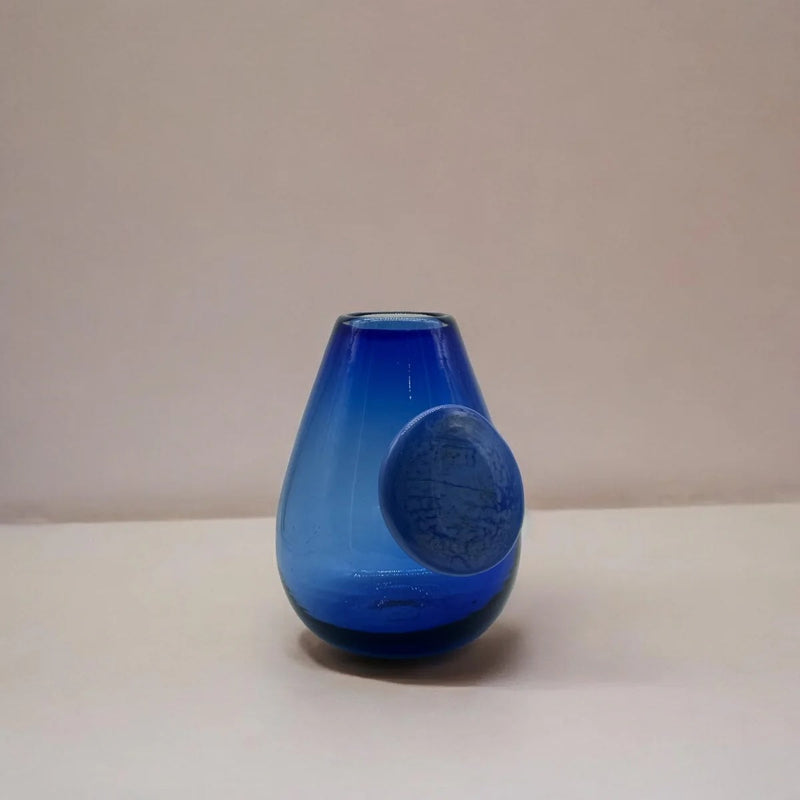 Blue glass vase with a round accent on a beige background