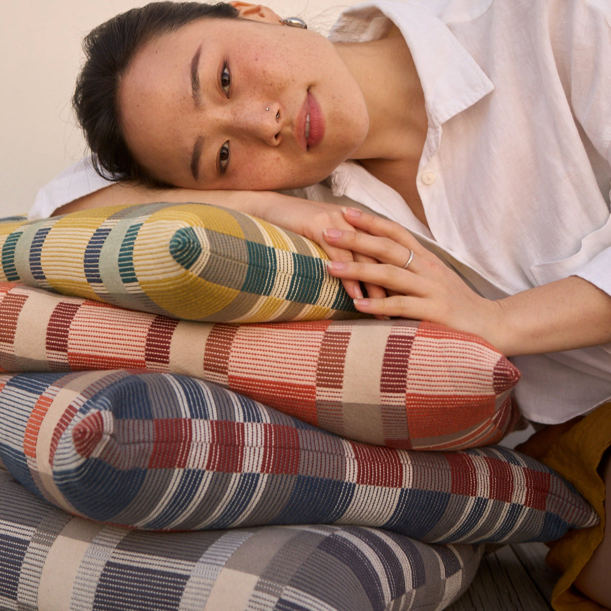 Woman lying on a stack of colorful patterned cushions
