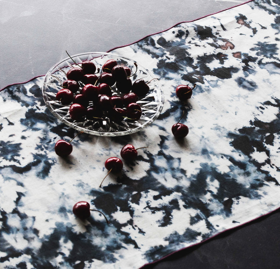 Cherries on a glass plate and scattered on a marble table runner