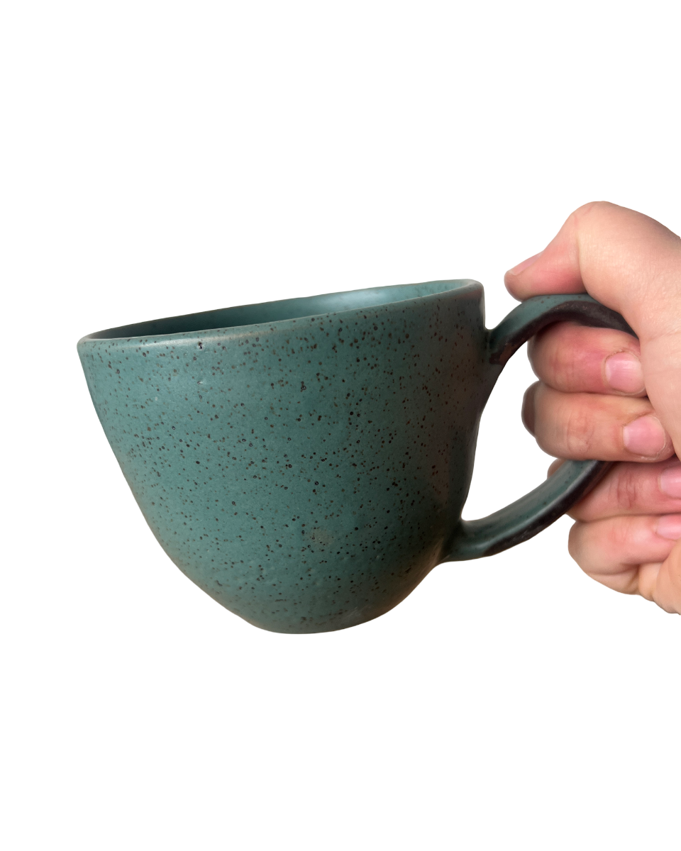 Hand holding a speckled teal mug on a white background