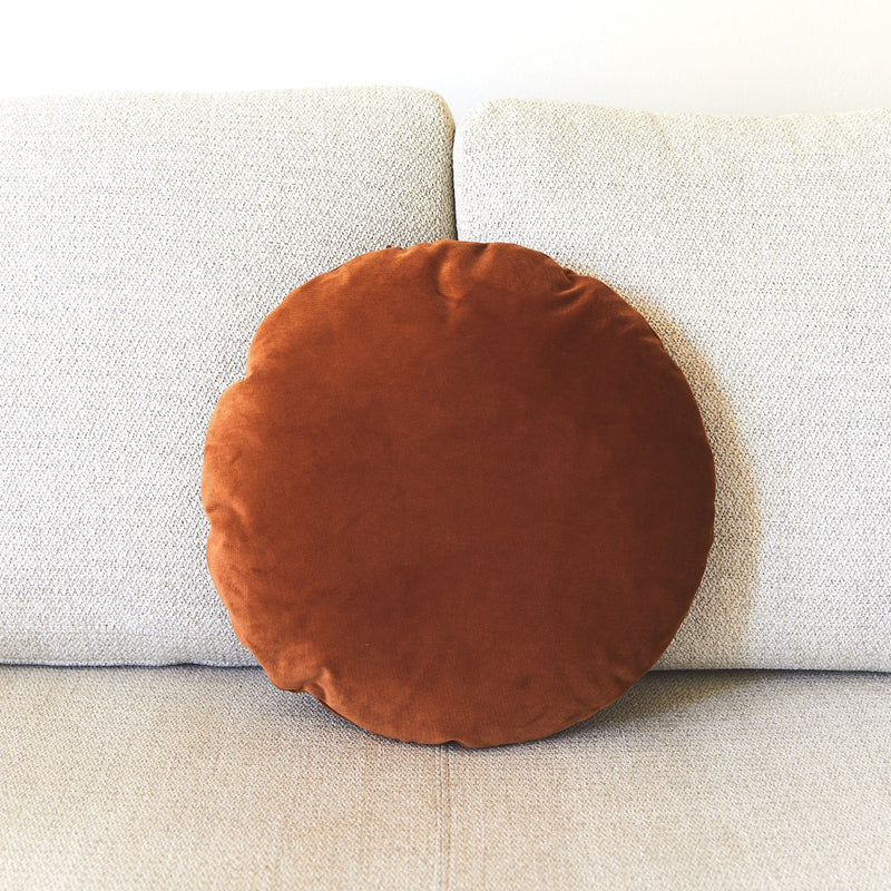 Round brown pillow on a light gray sofa
