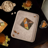 Tray with a geometric stone puzzle, popcorn, and almonds on a dark surface