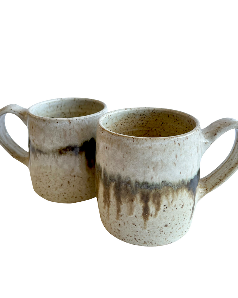 Two ceramic mugs with light and dark neutral glaze details on a white background