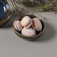 Small ceramic ramekin with macarons on a textured surface
