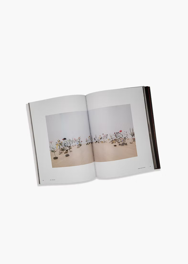 Open book showing a photograph of a gallery setting with flowers on a white background