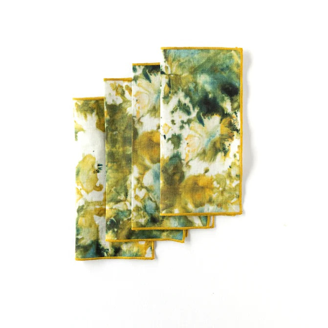 Set of green and gold marble patterned cocktail napkins folded on a white background