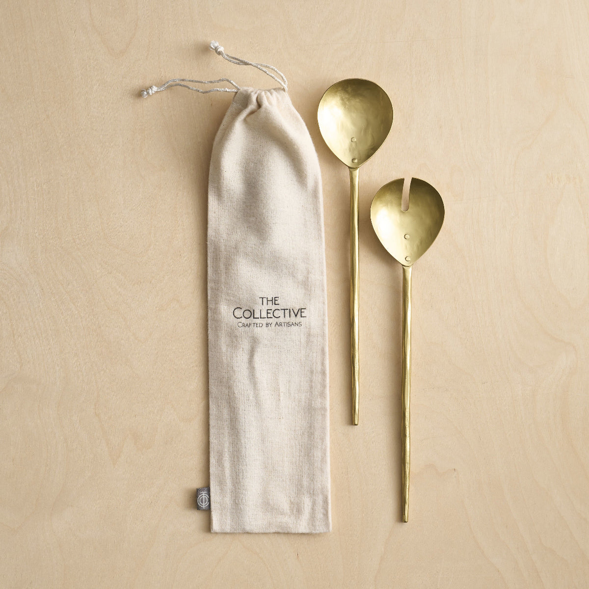 Brass Serving Spoons with cloth bag on a wooden surface