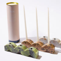 Decorative stone candle holders with candles and a cylindrical product packaging on a white background