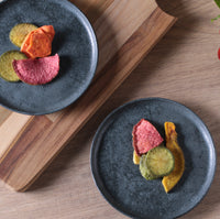 Two dark blue plates with colorful food on a wooden surface