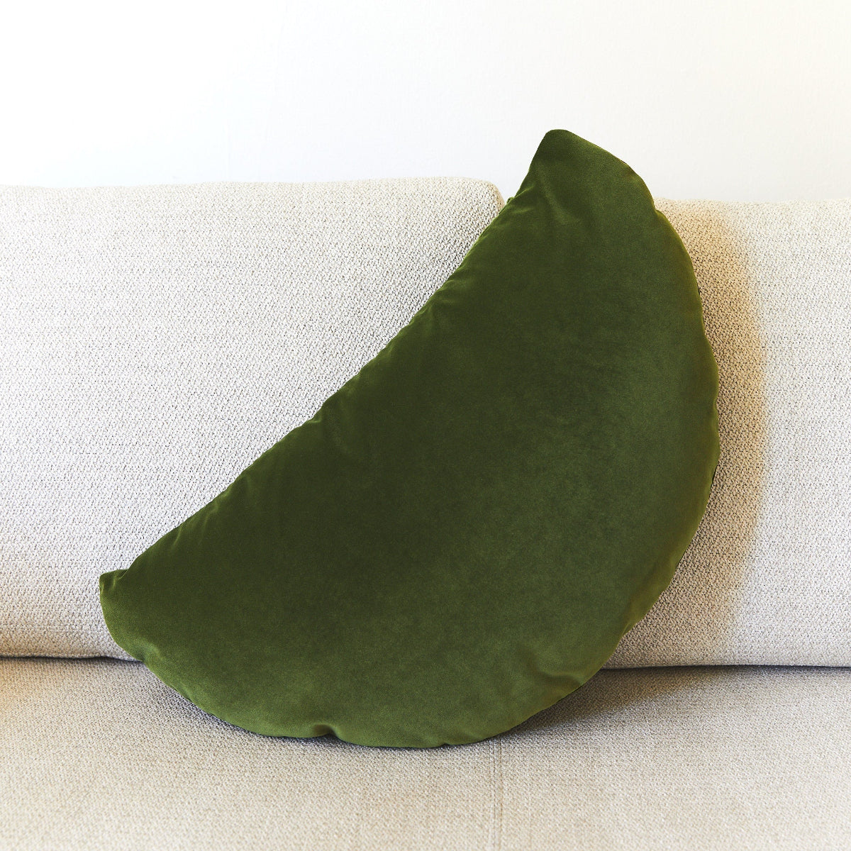Green crescent shaped pillow on a beige sofa