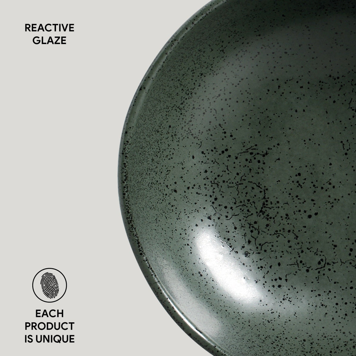 Close-up of a green ceramic bowl with reactive glaze on a light gray background