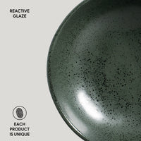 Close-up of a green ceramic bowl with reactive glaze on a light gray background