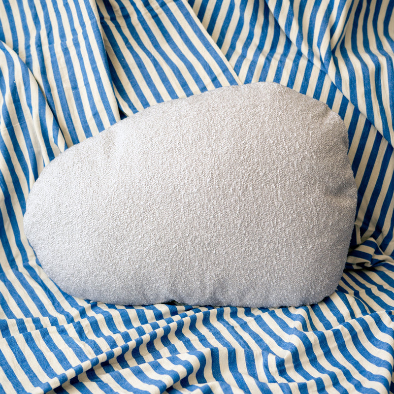 Light grey cloud-shaped pillow on blue and white striped fabric
