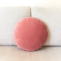Round pink cushion on a beige sofa