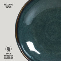 Close-up of a teal ceramic plate with reactive glaze on a light gray background.