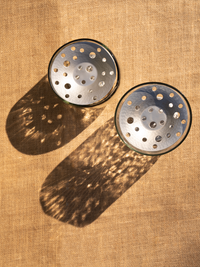 Two metallic round objects with holes on a textured brown surface