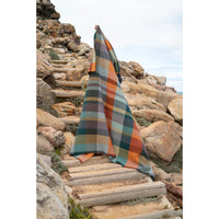 Plaid blanket draped over a stone staircase with a rocky landscape in the background