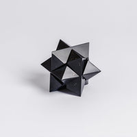 Black geometric polyhedron on a light gray background