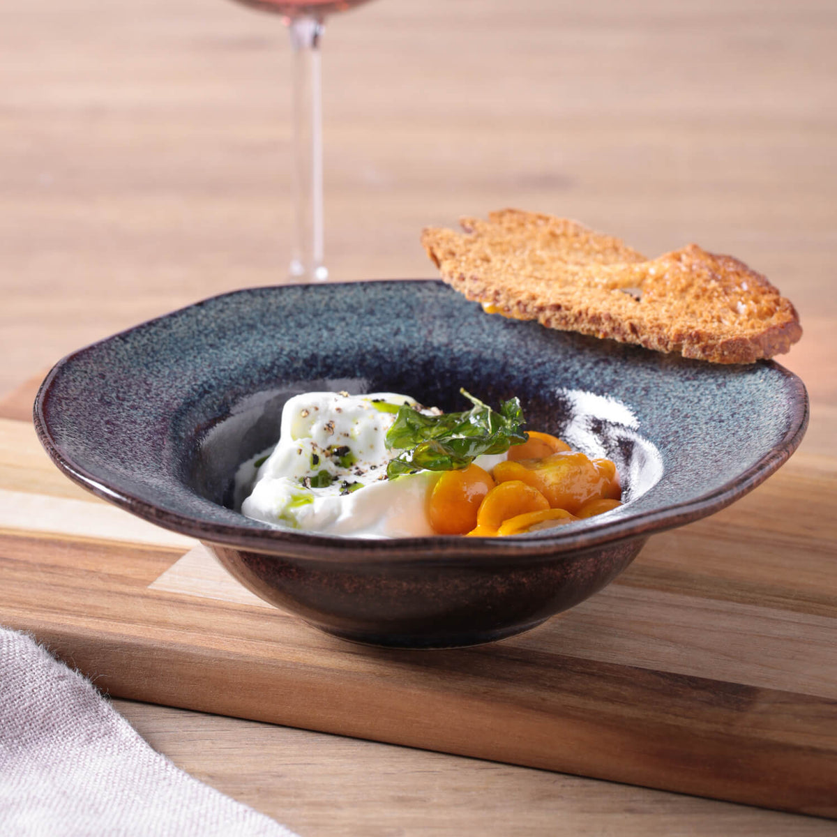 Dish with food on a wooden table with a glass of red wine in the background