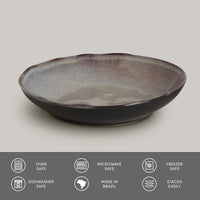 Ceramic pasta plate with speckled glaze on a light gray background