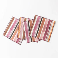 Set of four striped cocktail napkins in pink, brown, and black on a white background