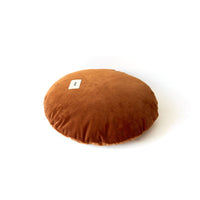 Round brown cushion with a label on a white background