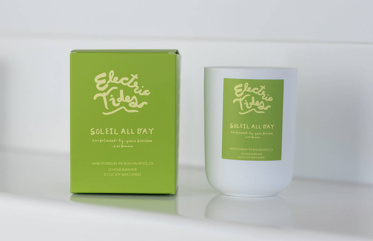 Candle and packaging of 'Electric Tides Soleil All Day' on a white background