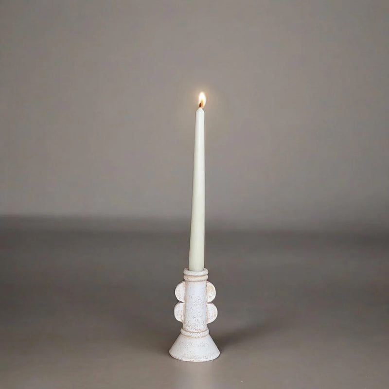 White candle in a decorative holder on a gray background