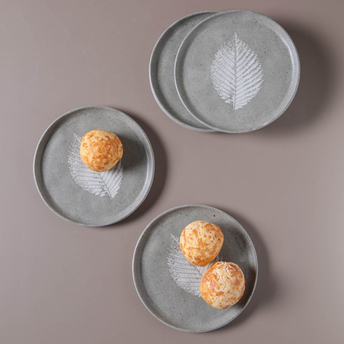 Set of gray ceramic plates with leaf design on a brown background