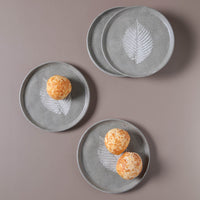 Set of gray ceramic plates with leaf design on a brown background