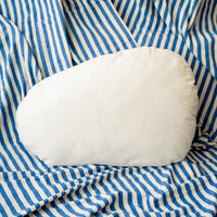 White crescent-shaped pillow on blue and white striped fabric