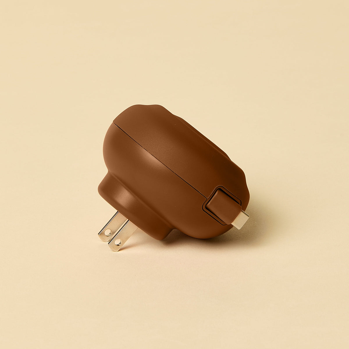 Brown wall plug and cord on a beige background