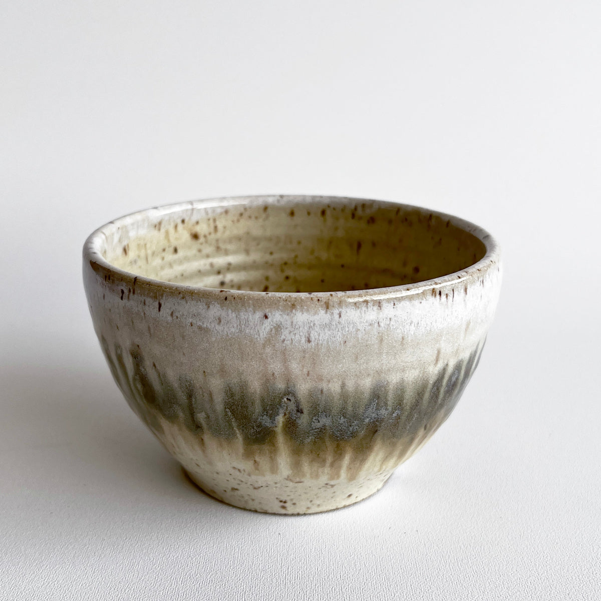 Ceramic bowl with light and dark neutral glaze details on a white background