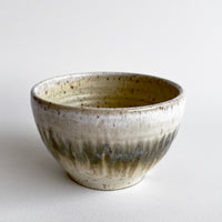 Ceramic bowl with light and dark neutral glaze details on a white background