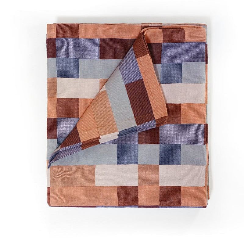 Folded checkered blanket with brown, blue, and beige squares