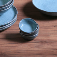 Stacked blue ceramic ramekins on a wooden surface