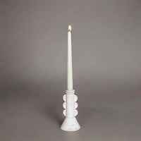 White candle in a decorative holder on a gray background