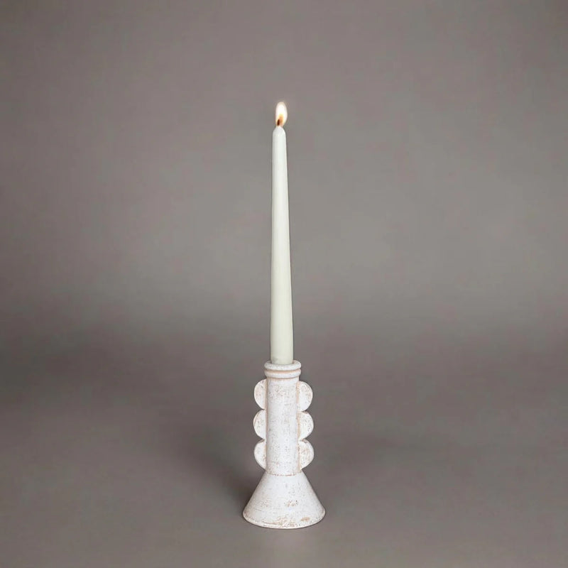 White candle in a decorative holder on a gray background