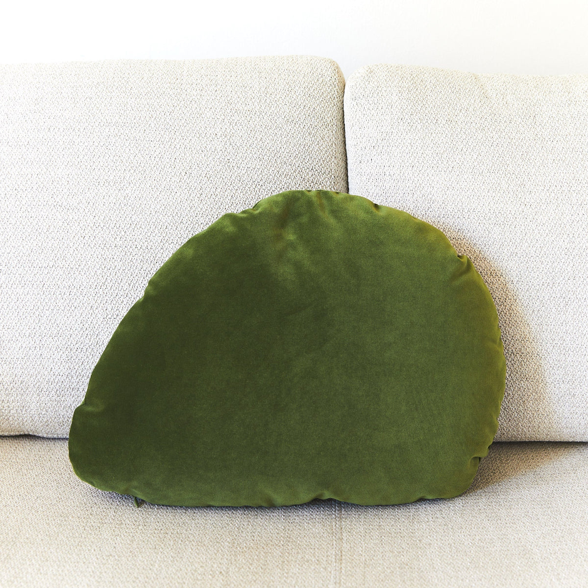 Green leaf-shaped pillow on a beige sofa
