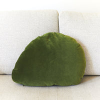Green leaf-shaped pillow on a beige sofa