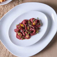 Plated dish of red meat with garnishes on a white plate